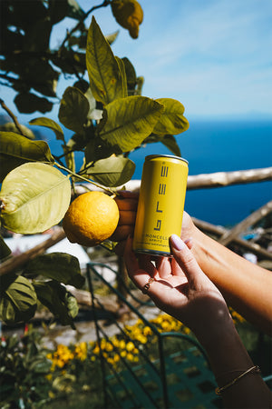 Eine Dose Bree Limoncello Spritz in der Hand einer Frau mit einer Zitrone